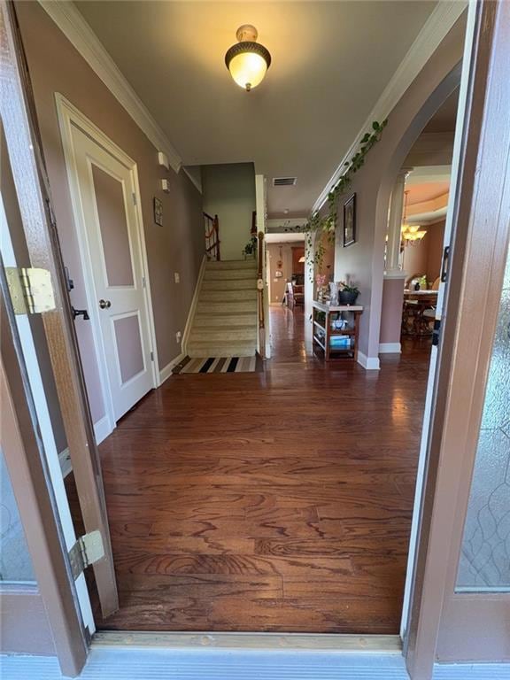 Foyer featuring arched walkways, wood finished floors, stairs, and ornamental molding