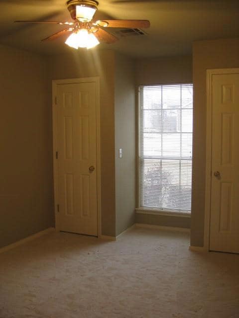 Empty room featuring plenty of natural light, a ceiling fan, and light carpet
