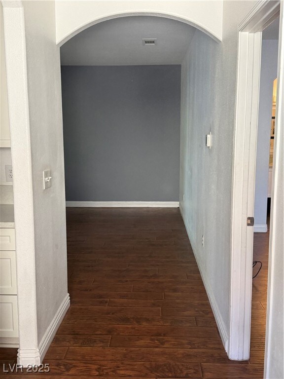 Corridor with dark wood-style flooring and arched