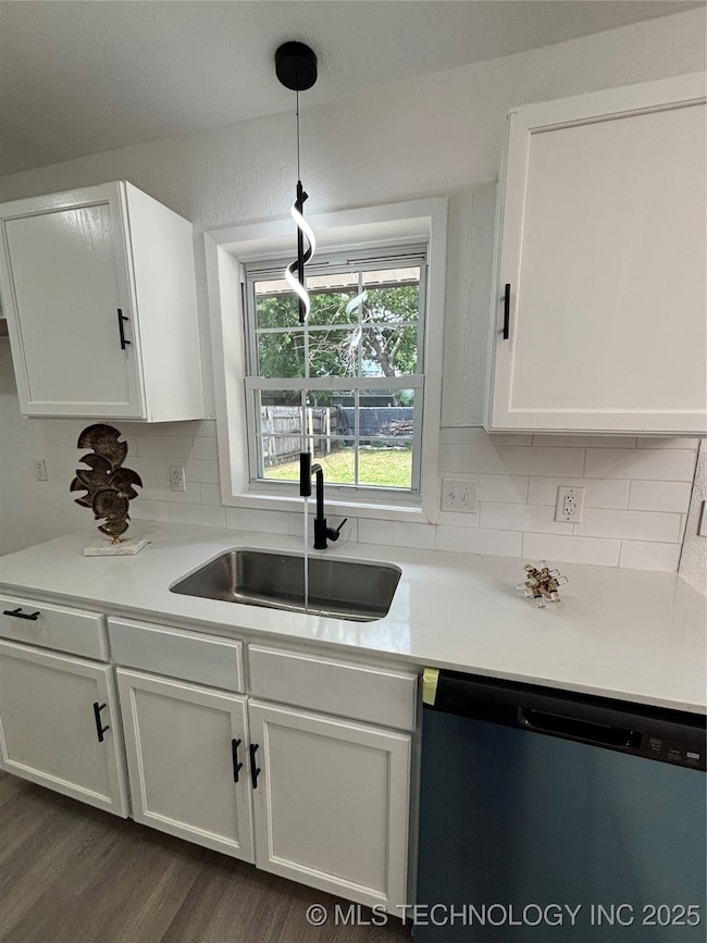 Kitchen with dishwasher, a sink, white cabinets, a