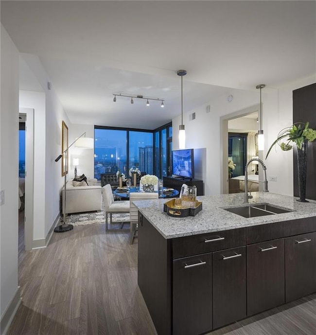 Kitchen with dark brown cabinetry, dark hardwood / wood-style floors, hanging light fixtures, rail lighting, and sink
