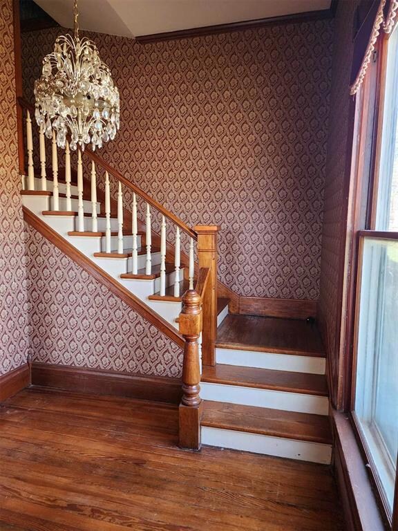 Stairway with an inviting chandelier and hardwood 