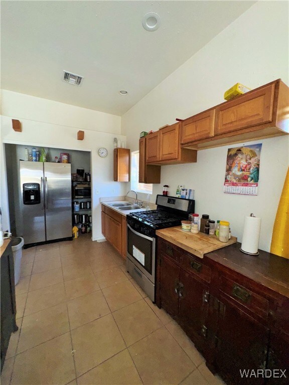 Kitchen with visible vents, appliances with stainless steel finishes, light tile patterned flooring, light countertops, and a sink