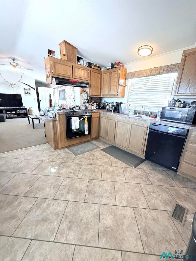 Kitchen with black appliances, a peninsula, ceiling fan, light tile patterned floors, and brown cabinetry