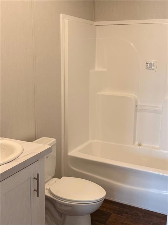 Bathroom with dark wood finished floors, vanity, and bathing tub / shower combination