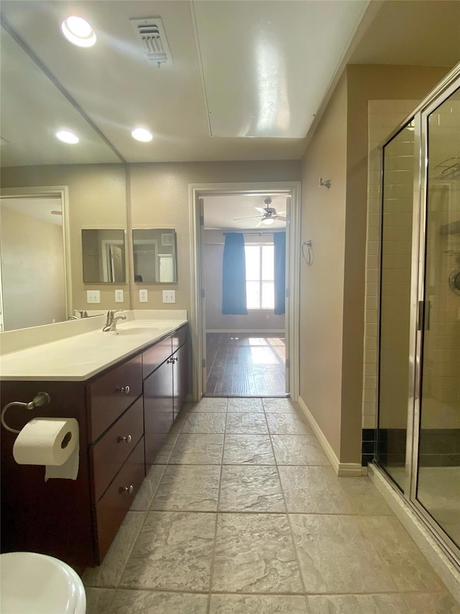 Bathroom with vanity, a stall shower, recessed lighting, ceiling fan, and stone tile flooring