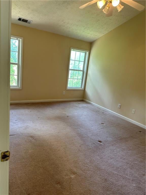Unfurnished room featuring a textured ceiling, ceiling fan, baseboards, and carpet floors