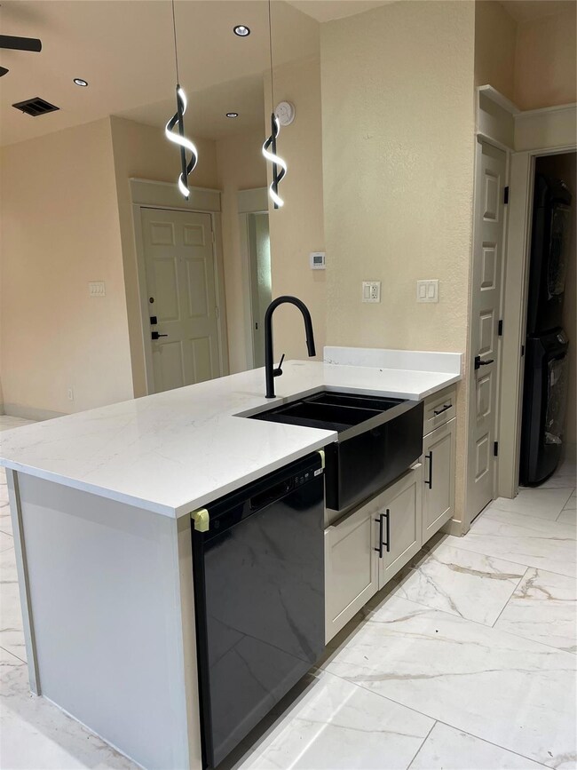 Kitchen featuring dishwashing machine, light stone