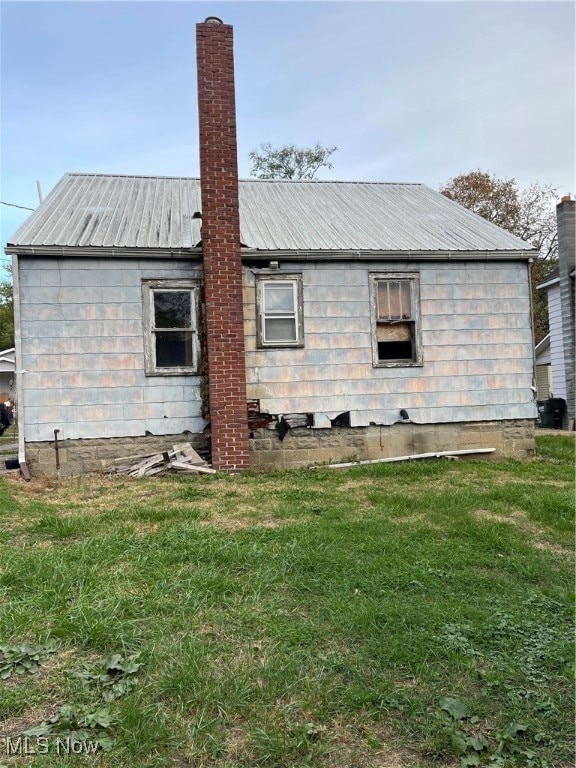 Rear view of property with a yard, a metal roof, and a chimney