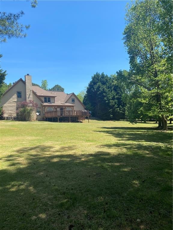 View of green lawn featuring a wooden deck