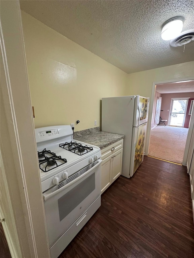 Kitchen featuring white appliances, a textured cei