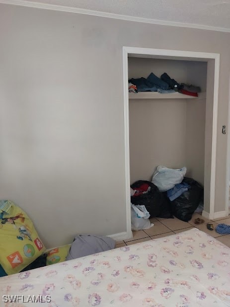 Tiled bedroom with a closet, crown molding, and ba
