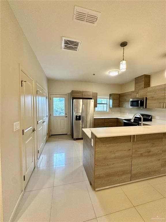 Kitchen with a peninsula, appliances with stainless steel finishes, modern cabinets, light tile patterned flooring, and pendant lighting