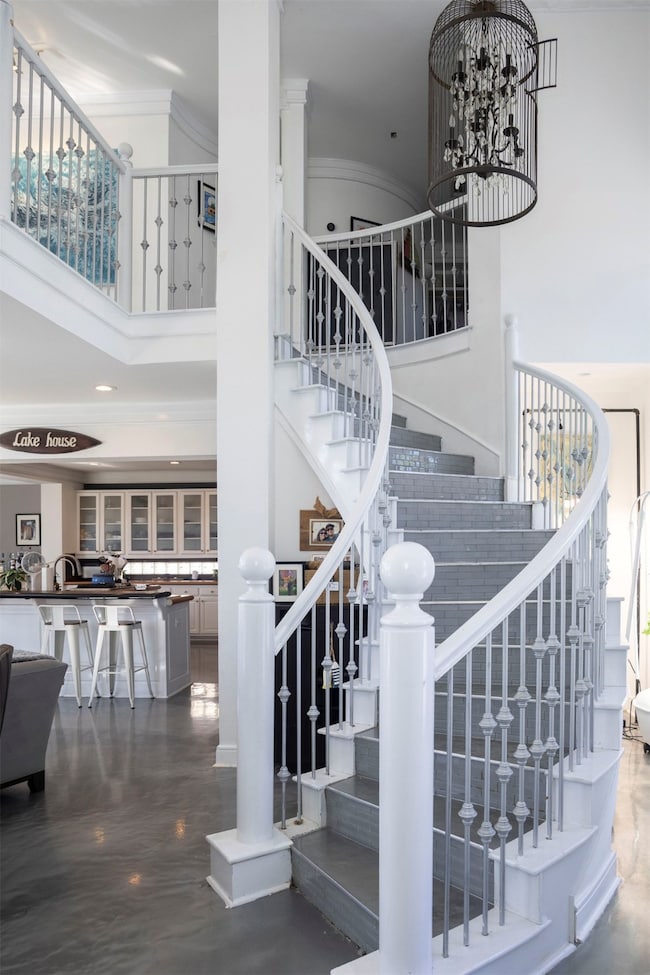 Staircase with a high ceiling, a chandelier, and crown molding