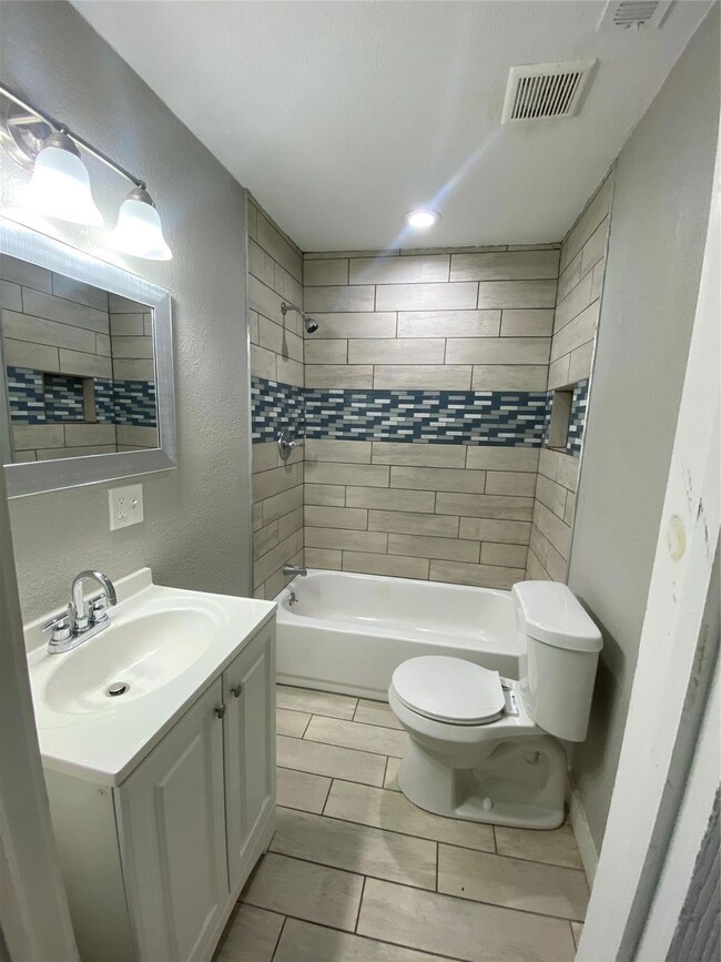 Full bathroom featuring tiled shower / bath, tile flooring, toilet, and vanity