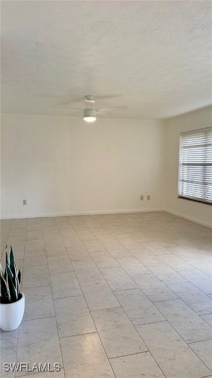 Spare room with a textured ceiling, ceiling fan, a