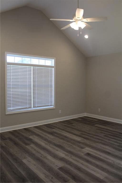 Empty room featuring dark wood finished floors, vaulted ceiling, ceiling fan, and recessed lighting