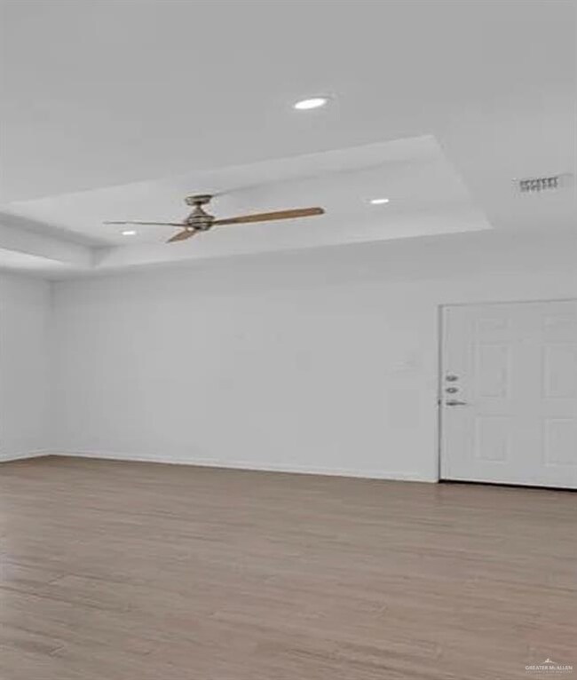 Spare room with a raised ceiling, light wood-type flooring, a ceiling fan, and recessed lighting