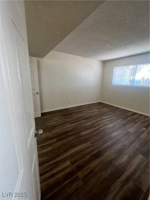 Unfurnished room featuring dark wood-style floors, a textured wall, and a textured ceiling
