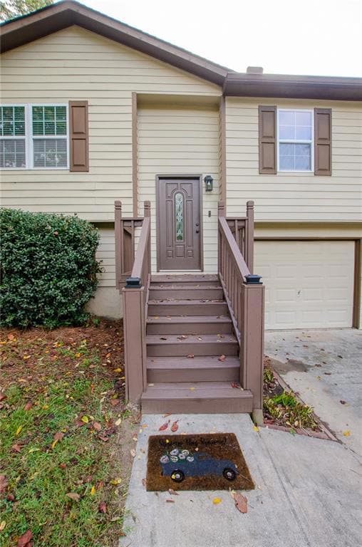 Entrance to property featuring concrete driveway and a garage
