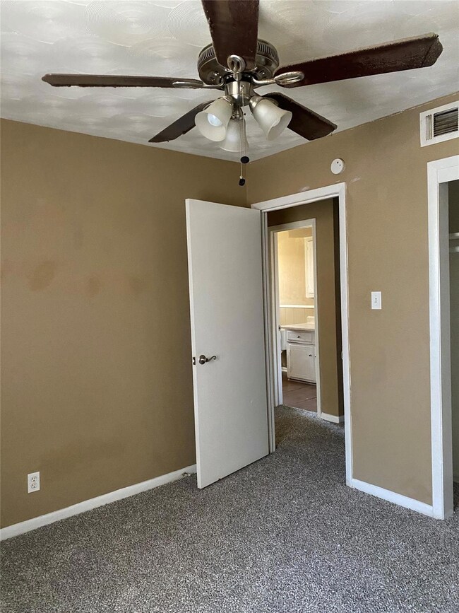 Unfurnished bedroom with dark carpet, visible vent
