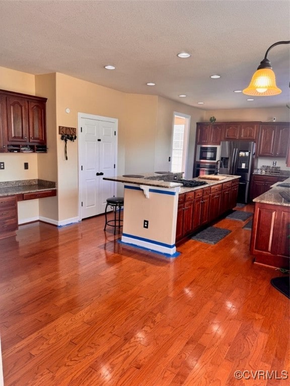 Kitchen with fridge, dark wood-style floors, a kit