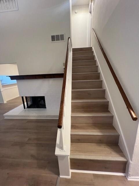 Stairway with visible vents, a fireplace, and wood