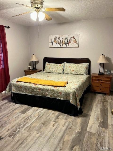 Bedroom with wood finished floors, a textured ceiling, and ceiling fan