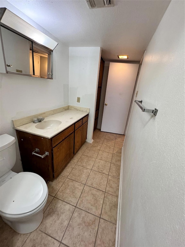 Bathroom featuring a textured ceiling, vanity, til