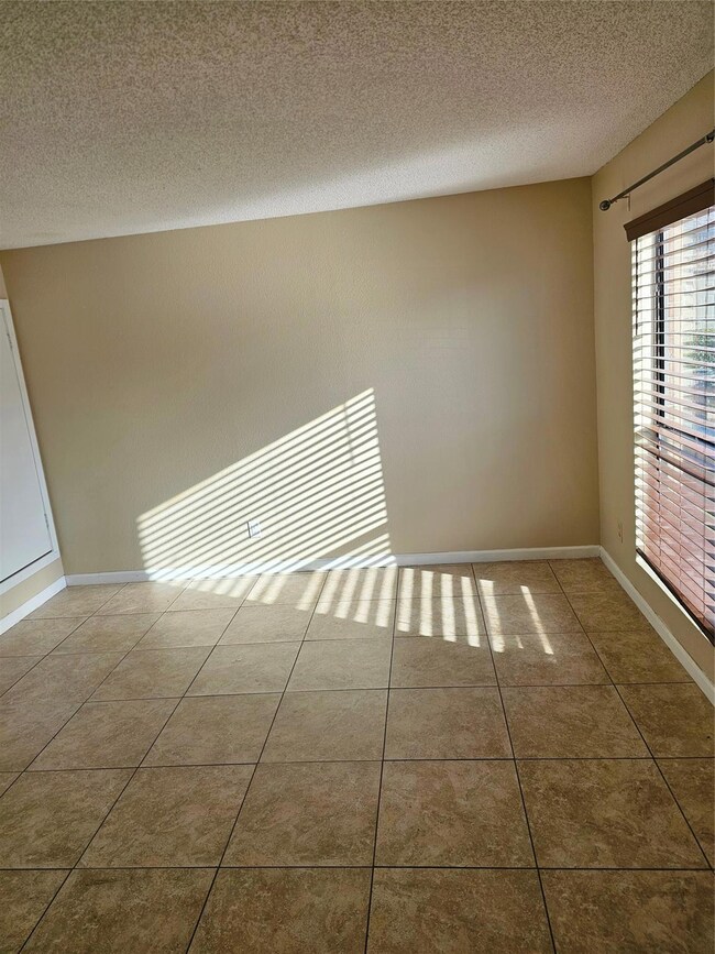 Tiled empty room featuring a textured ceiling