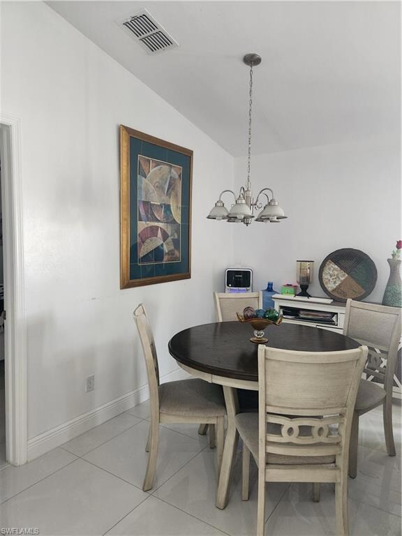 Dining area with tile floors, a chandelier, and va
