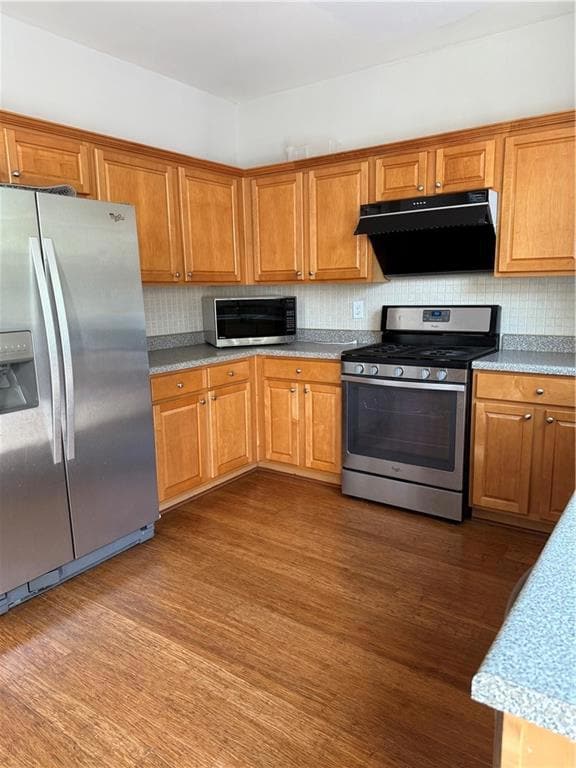 Kitchen featuring refrigerator, range, extractor fan, dark wood-style floors, and decorative backsplash