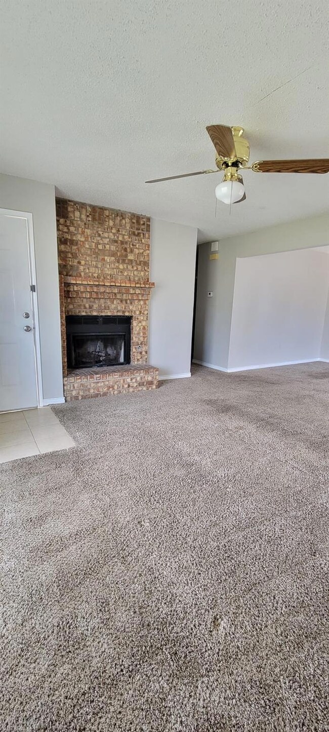 Unfurnished living room with carpet flooring, a textured ceiling, a fireplace, and ceiling fan