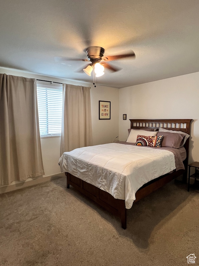 Carpeted bedroom with ceiling fan and a textured ceiling