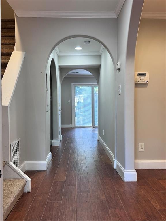 Corridor featuring dark wood-type flooring, crown molding, and stairs