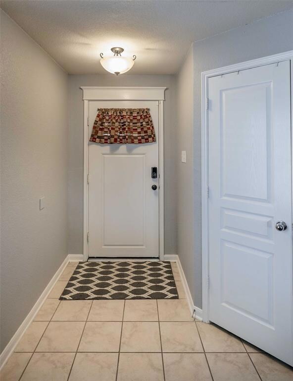 Entryway features tile flooring & a coat closet.