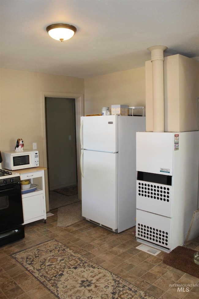 Kitchen featuring white appliances and stone finish floors