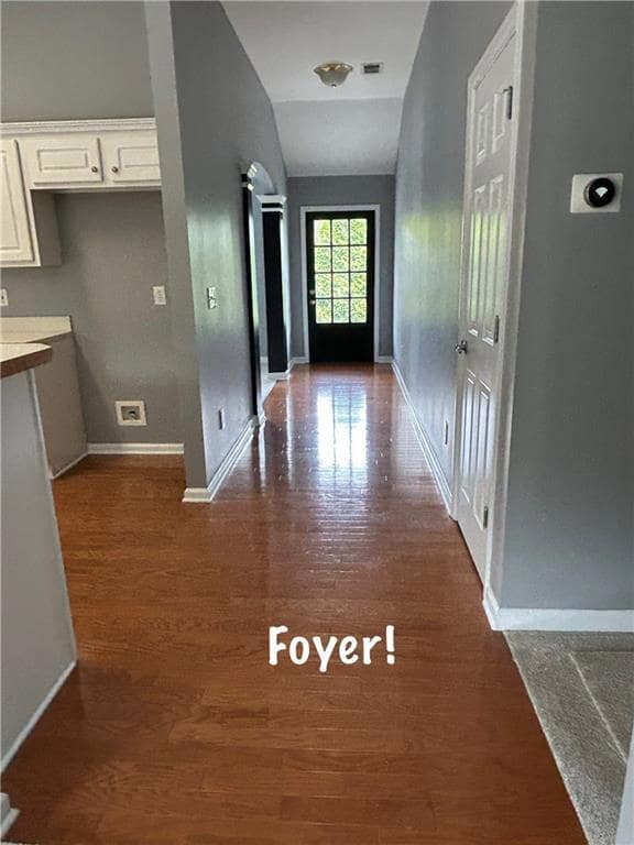 Corridor with dark wood-style floors, baseboards, 