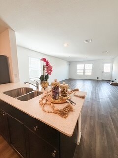 Kitchen with dark wood finished floors, open floor plan, dark cabinets, and light stone countertops
