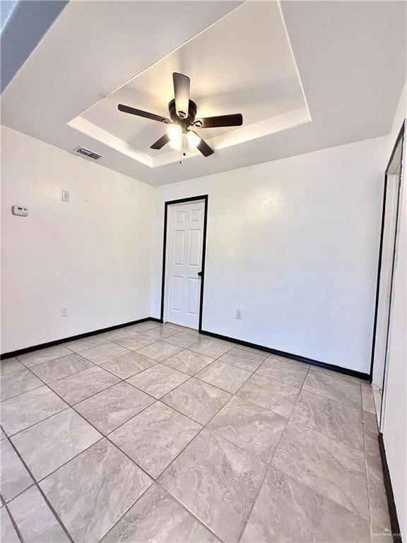 Spare room with a raised ceiling and a ceiling fan