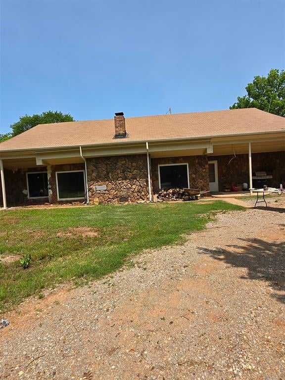 Another view of front of earth sheltered home featuring stone siding & a chimney.