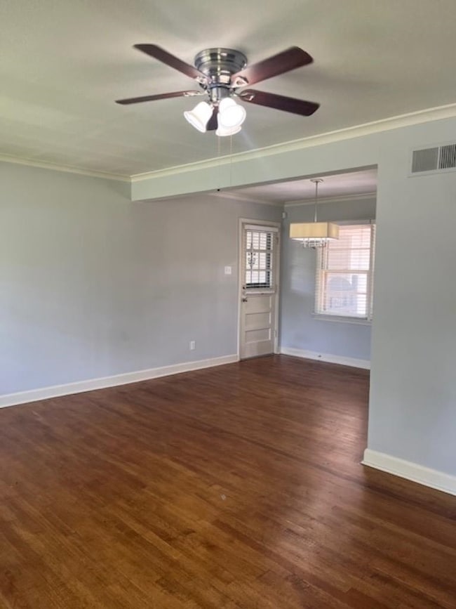 Empty room featuring crown molding, baseboards, wood finished floors, and ceiling fan
