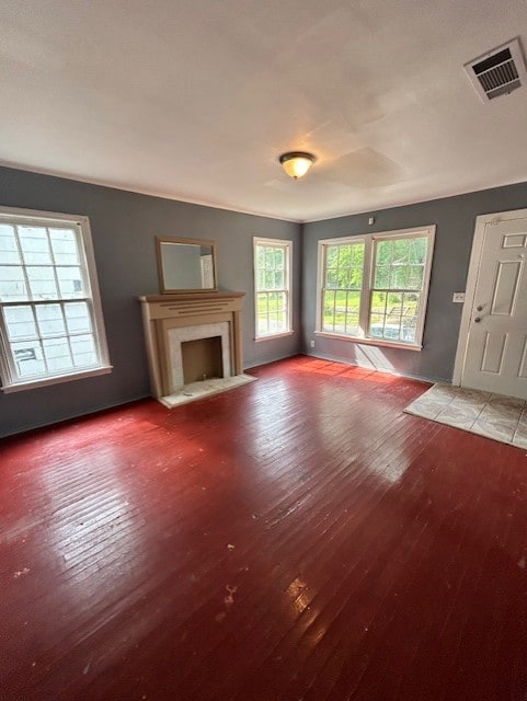 Unfurnished living room featuring dark wood-style floors, a fireplace with flush hearth, and plenty of natural light
