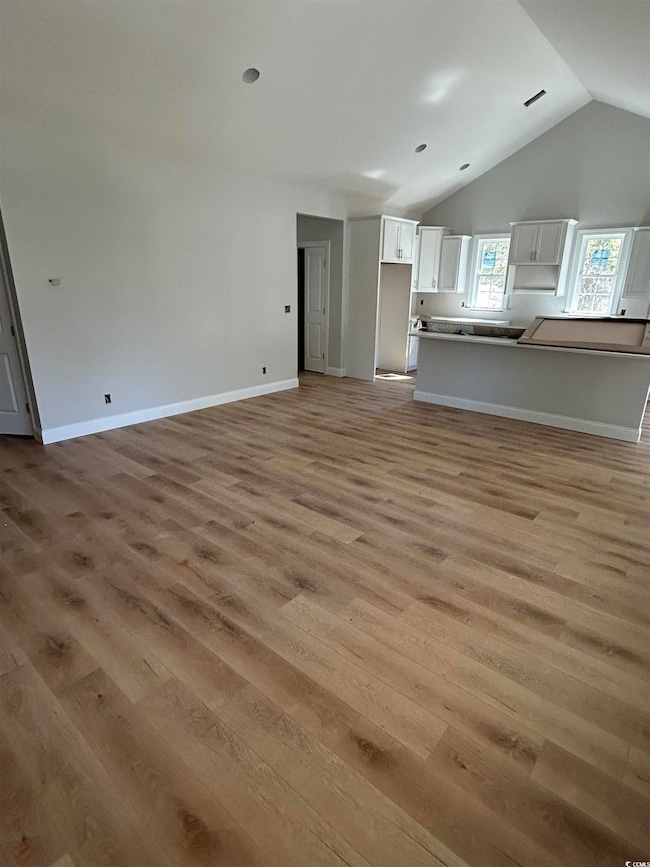Unfurnished living room with baseboards, light woo