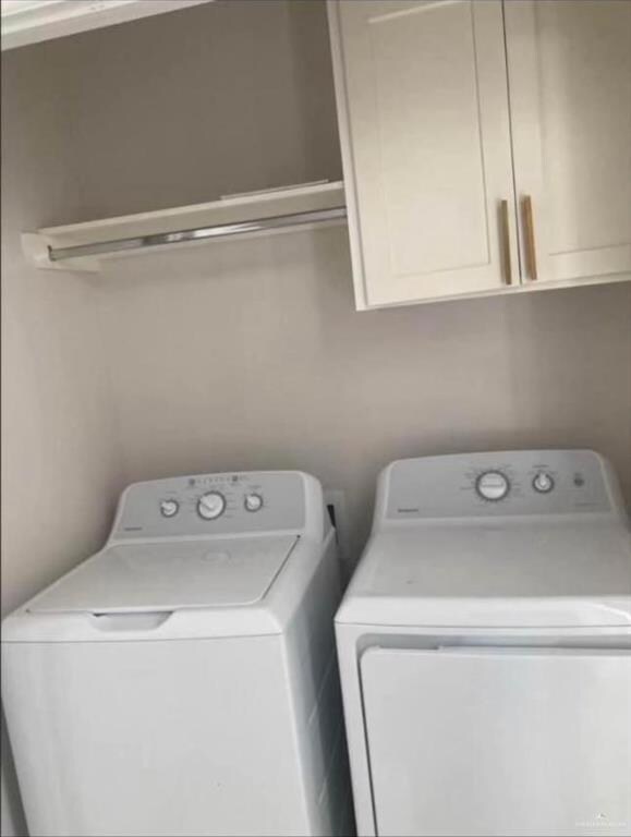 Washroom featuring cabinets and washing machine and dryer