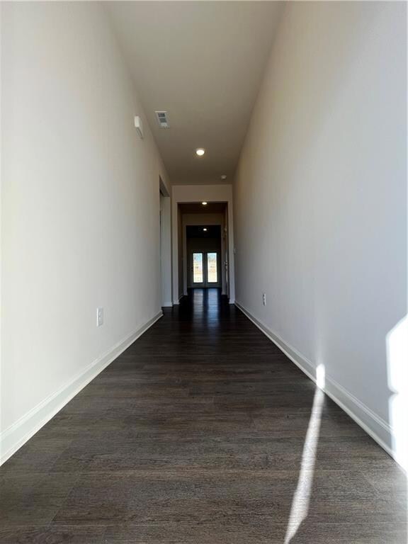 Corridor with dark wood-style floors, baseboards, 