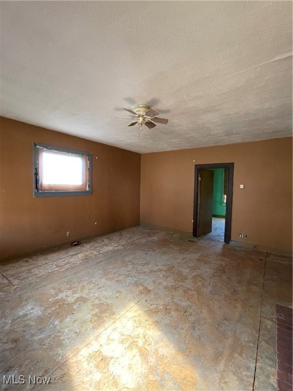 Empty room featuring ceiling fan and a textured ceiling