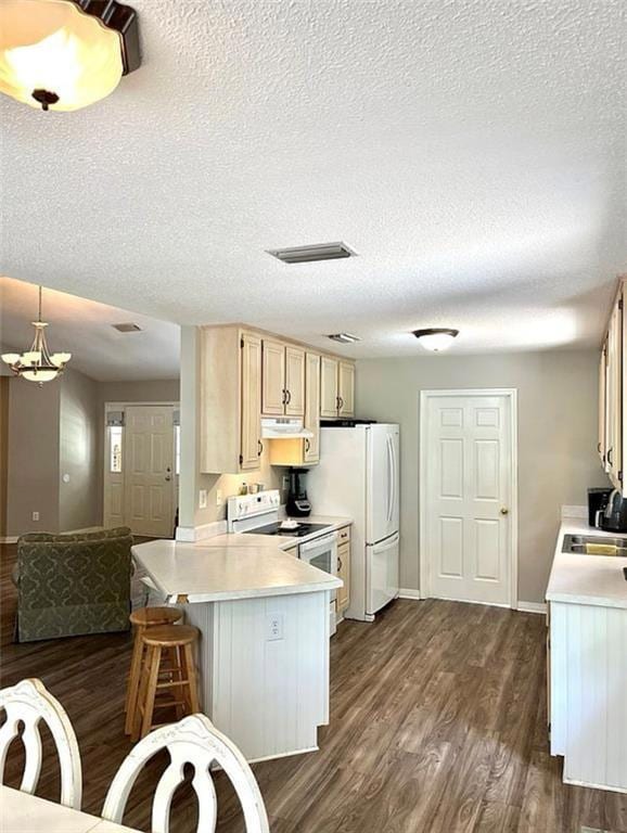 Kitchen with white appliances, light countertops, a textured ceiling, and a peninsula