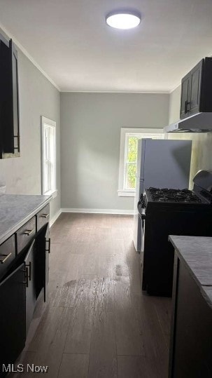 Kitchen with black gas stove, light countertops, ornamental molding, dark wood finished floors, and dark cabinets