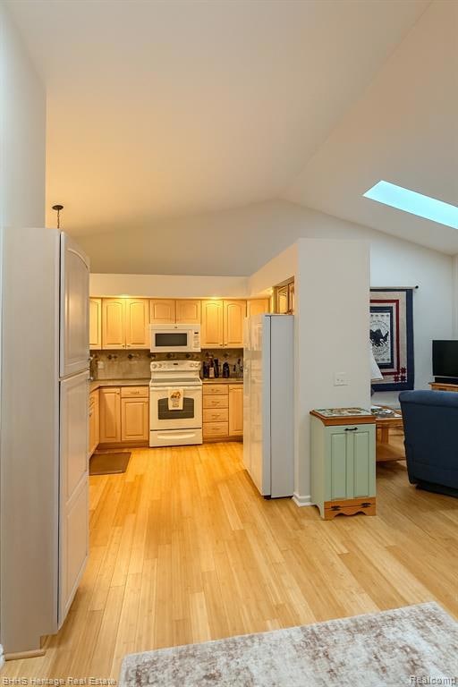 Kitchen with a skylight, white appliances, light wood-type flooring, lofted ceiling, and tasteful backsplash